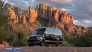Luxury Mercedes Sprinter van parked with Sedona’s iconic red rock formations in the background, showcasing comfort and style for group travel or events.